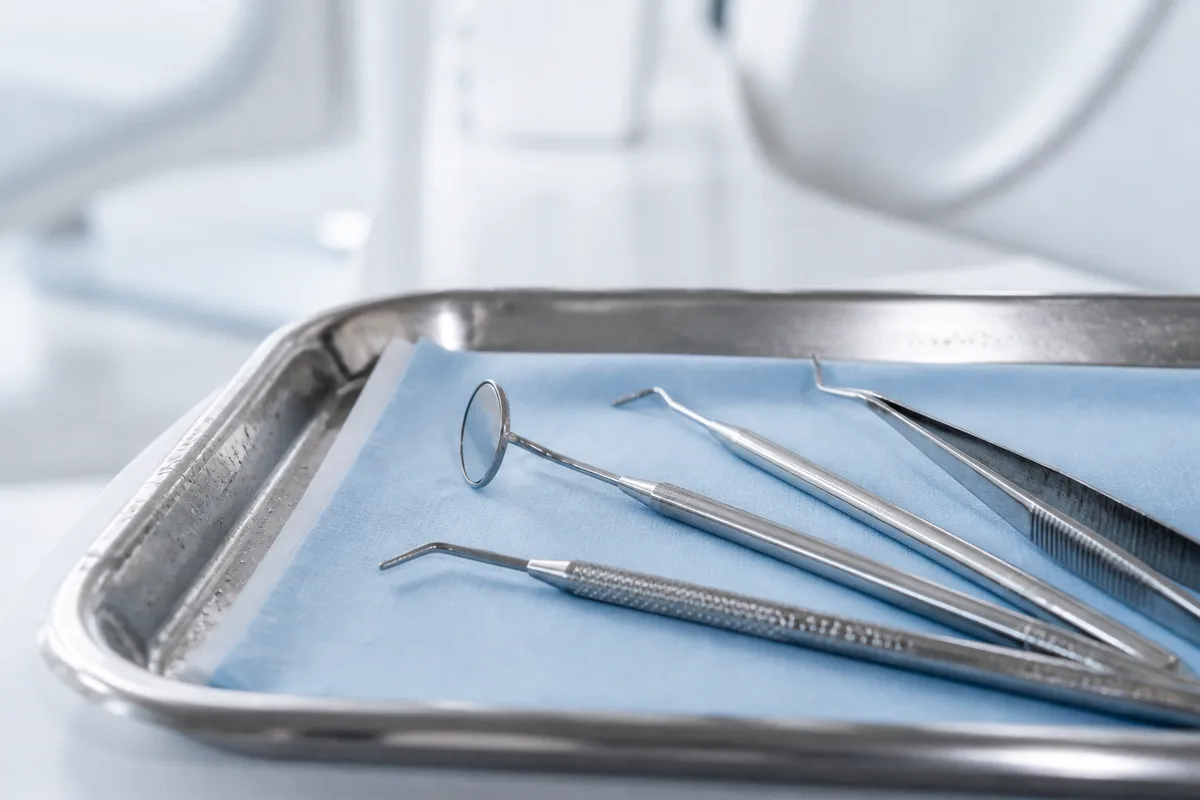 Instruments dentaires alignés sur un plateau en inox, lumière douce de cabinet